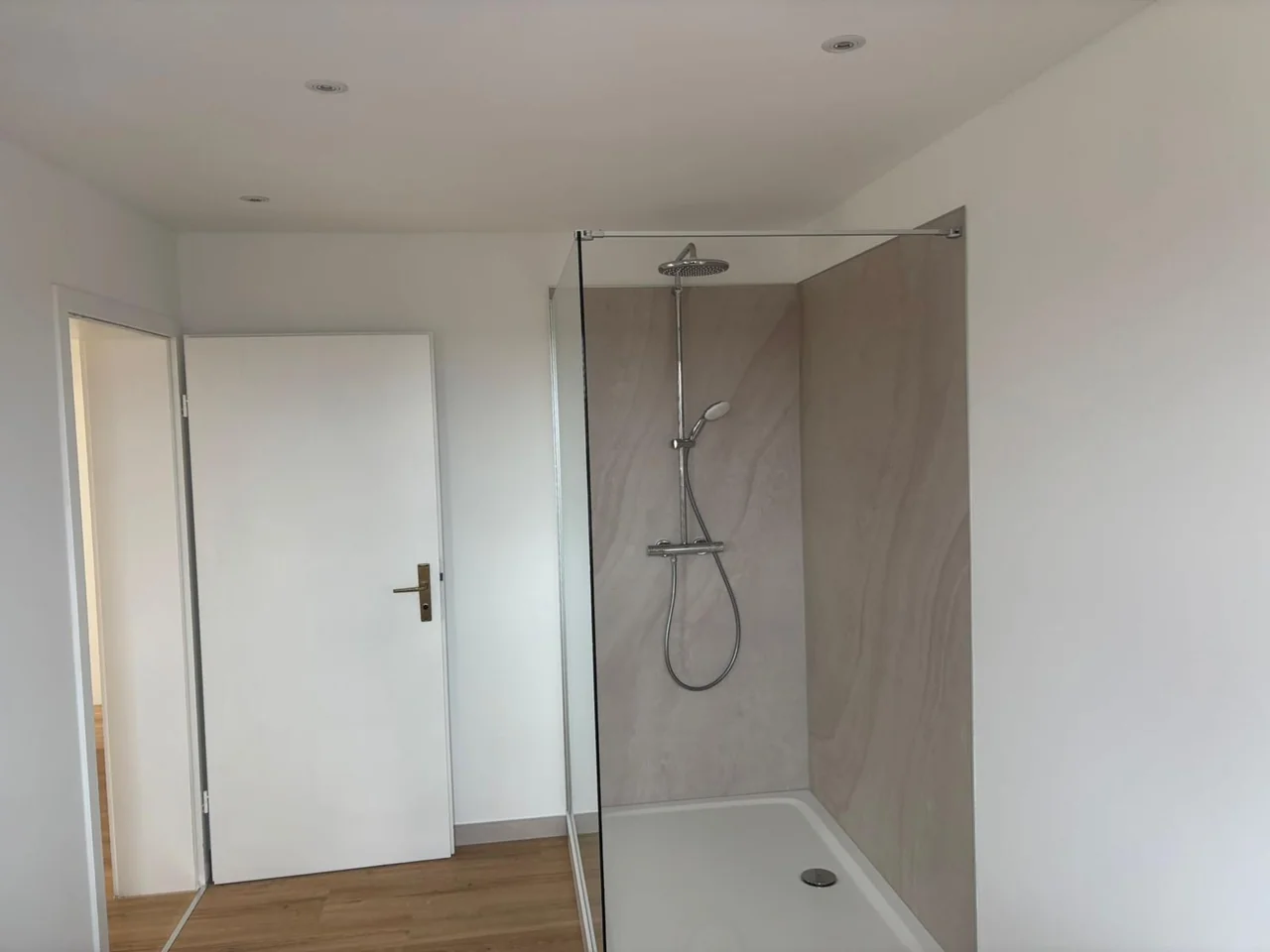 Badezimmer mit Glasdusche, großflächiger Wandverkleidung und Boden in Holzoptik